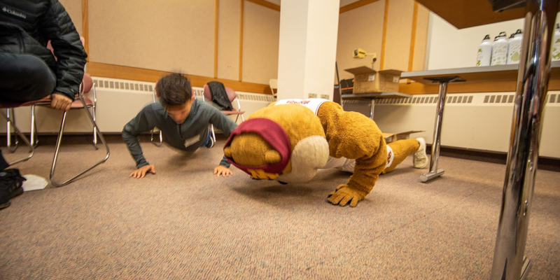 Goldy Gopher and a student compete in a pushup contest.