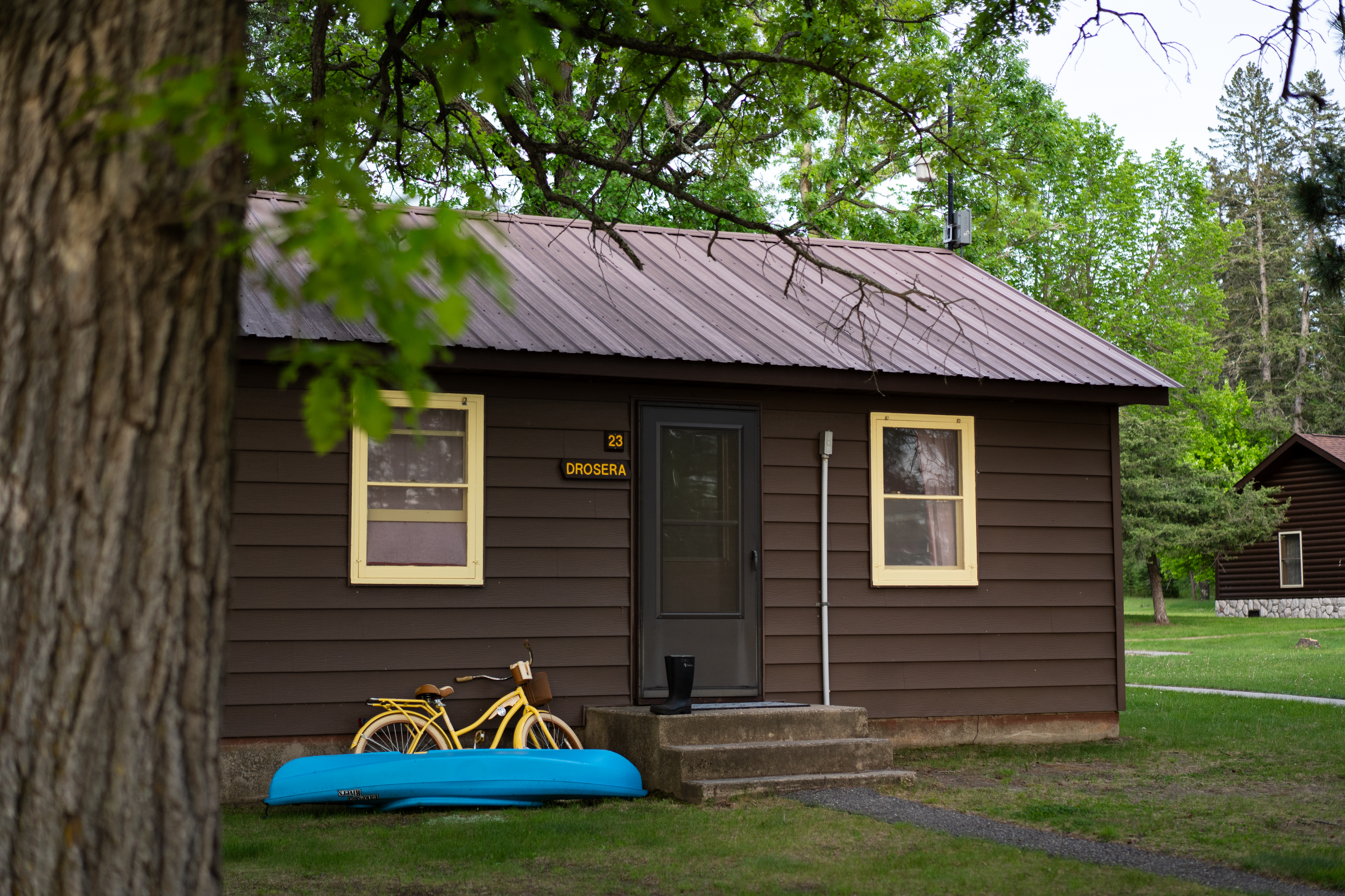 Student bunkhouse cabin #23 at Itasca Station, with a yellow bicycle and blue kayak leaning against the front of the building.