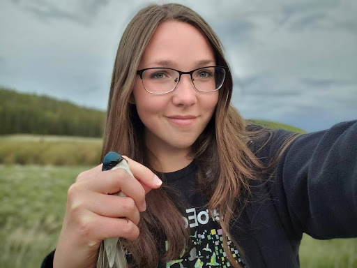 Itasca Station Scientist Victoria Simons holding a small bird and smiling