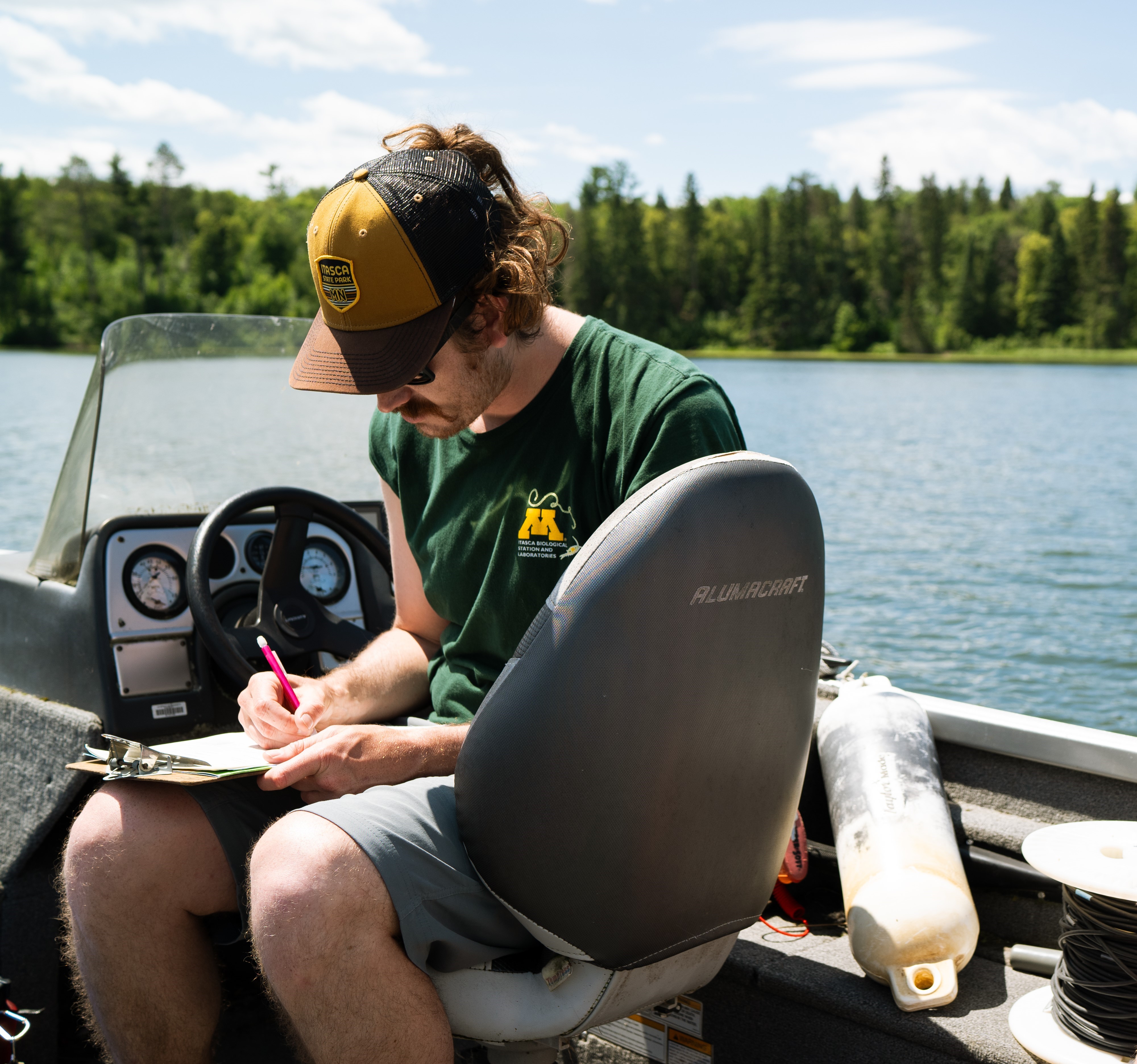 A researcher in a boat, writing on a clip board