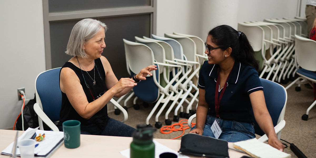 Elizabeth Borer speaking with a collaborator at the DRAGNet conference