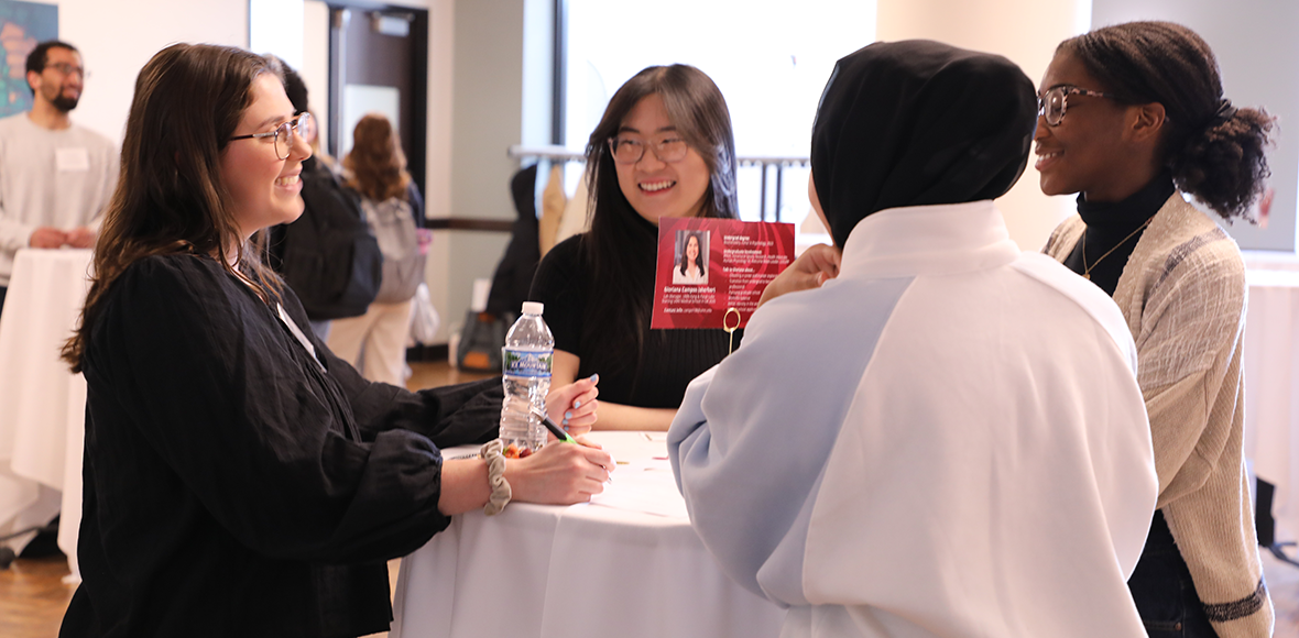 Group of students networking with a CBS alumni. 