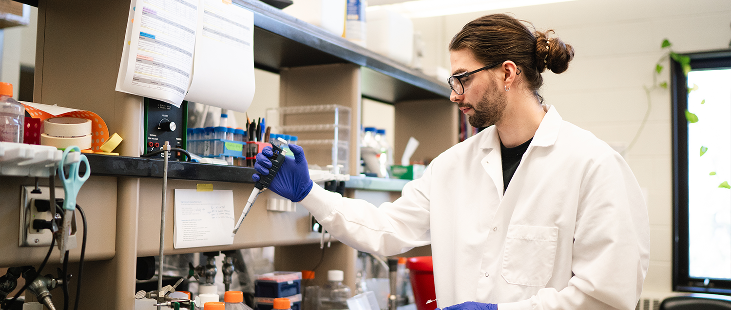 Graduate student working in a lab with pipette