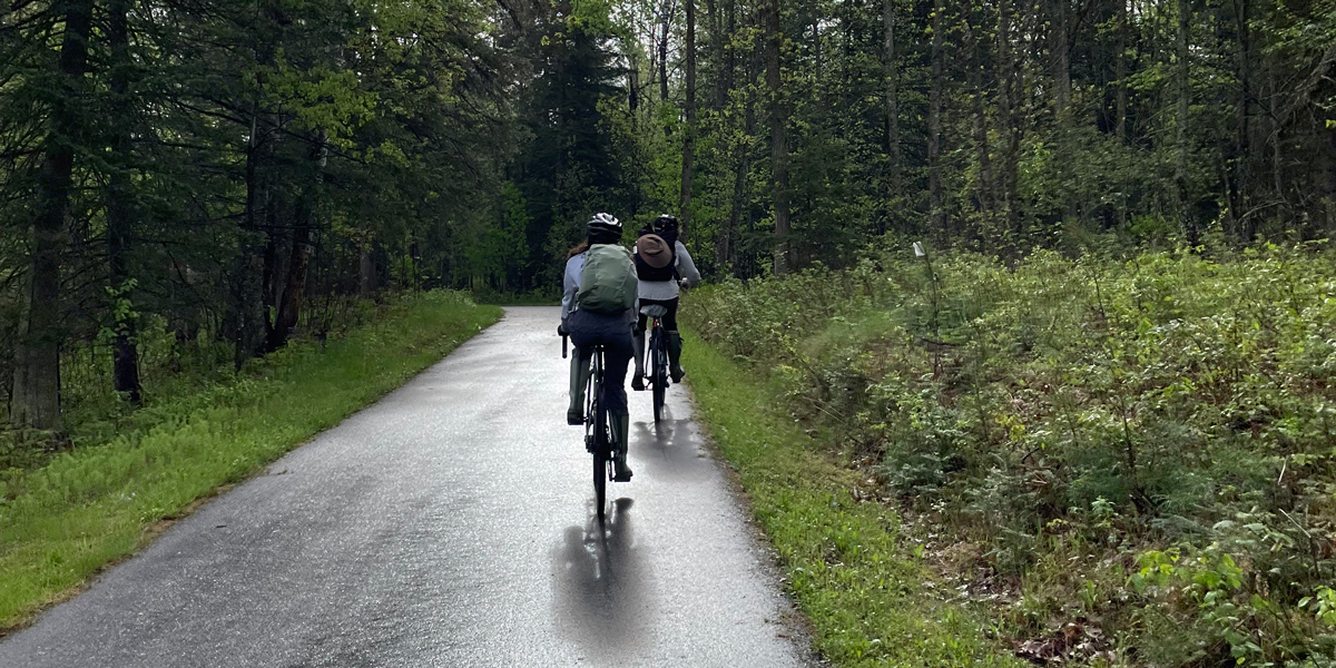 Two people bike down path in the woods at Itasca State Park