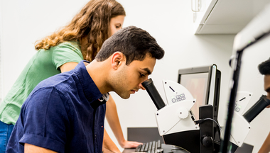 Students looking at microscope and computer
