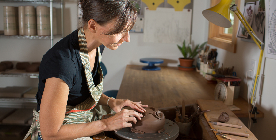Photograph of the artist Ursula Hargens sitting at a pottery wheel in a studio