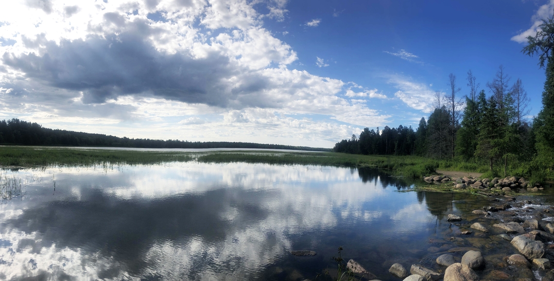 The Lake Itasca Mississippi Headwaters on a sunny day, with the clouds in the sky reflecting on the lake
