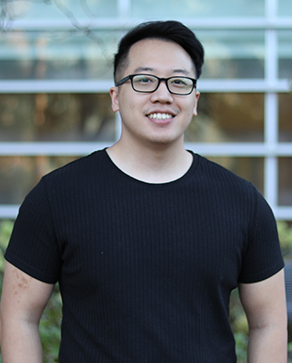 Pheng wears glasses and a black t-shirt and has black hair combed to one side.