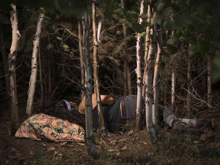 researcher lying on a pillow on the ground under trees