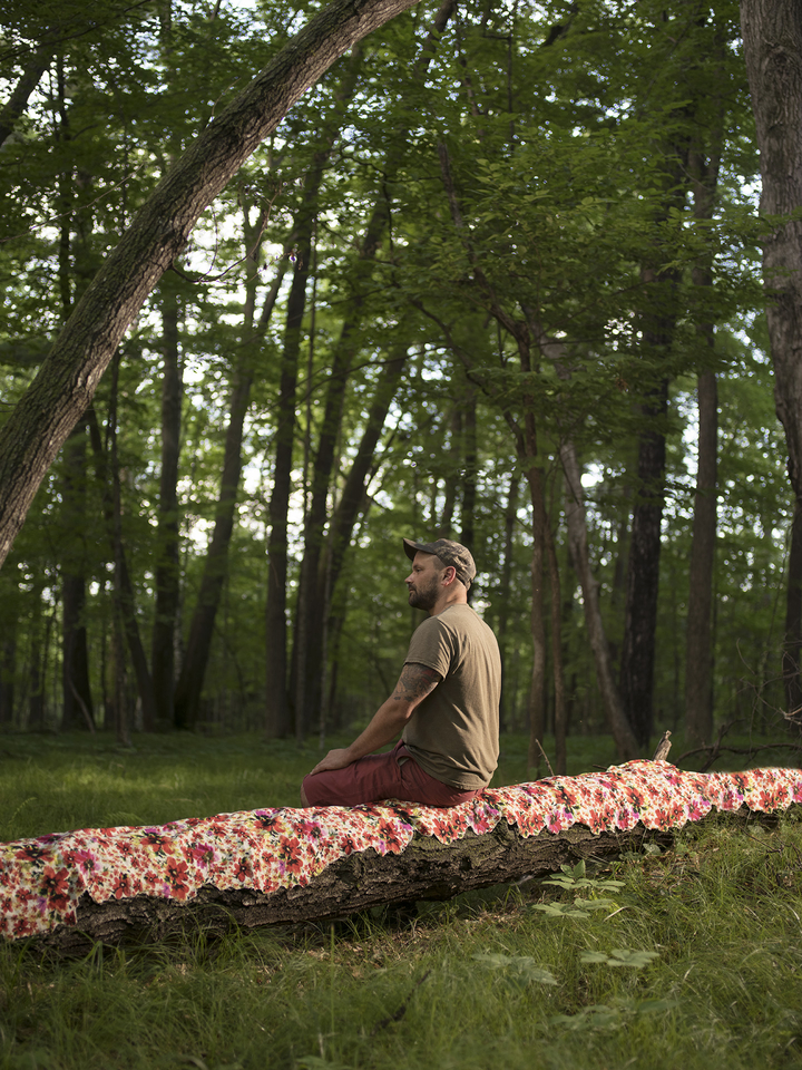 researcher sitting on a fabric-covered log in the forest
