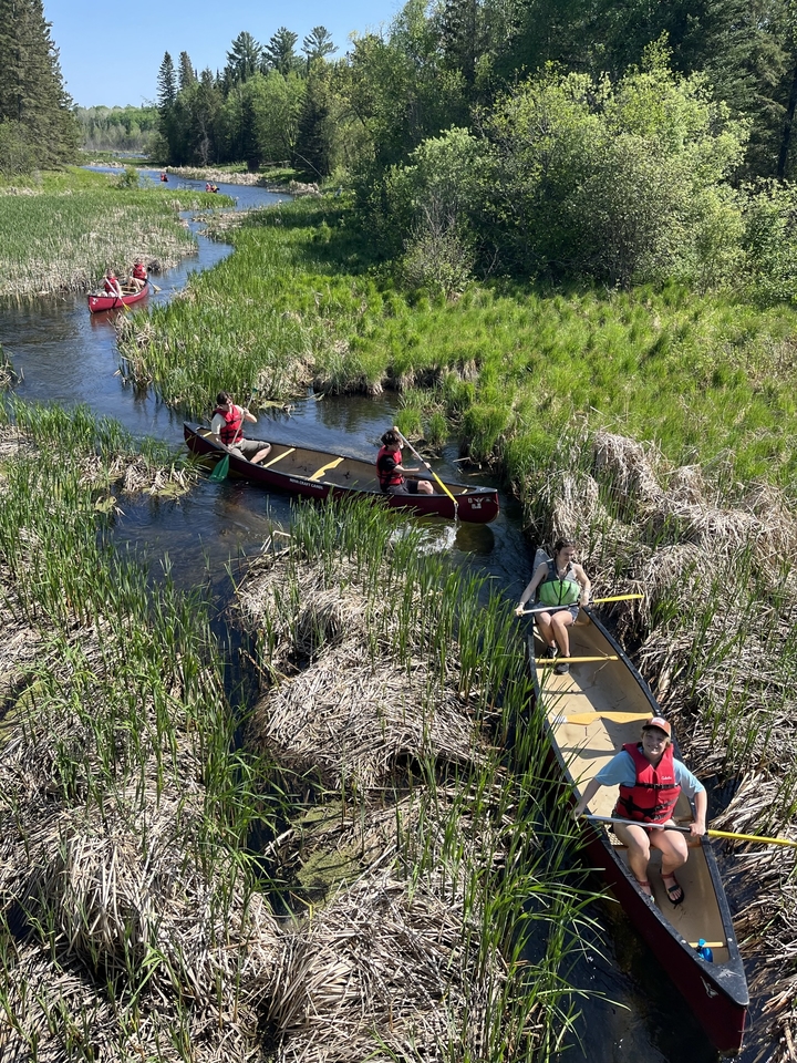 Students in canoes in a marshy area of the early Mississippi river